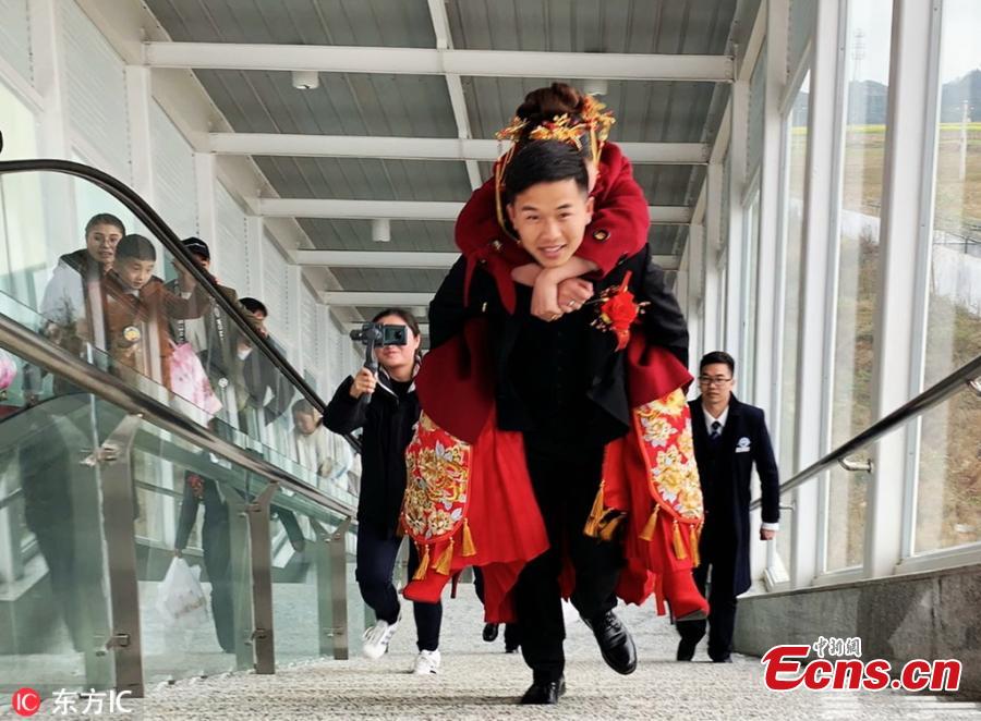 He Xueqiang carries his bride on his back to board a high-speed train at a railway station in Guangnan County, Yunnan Province. (Photo/IC)