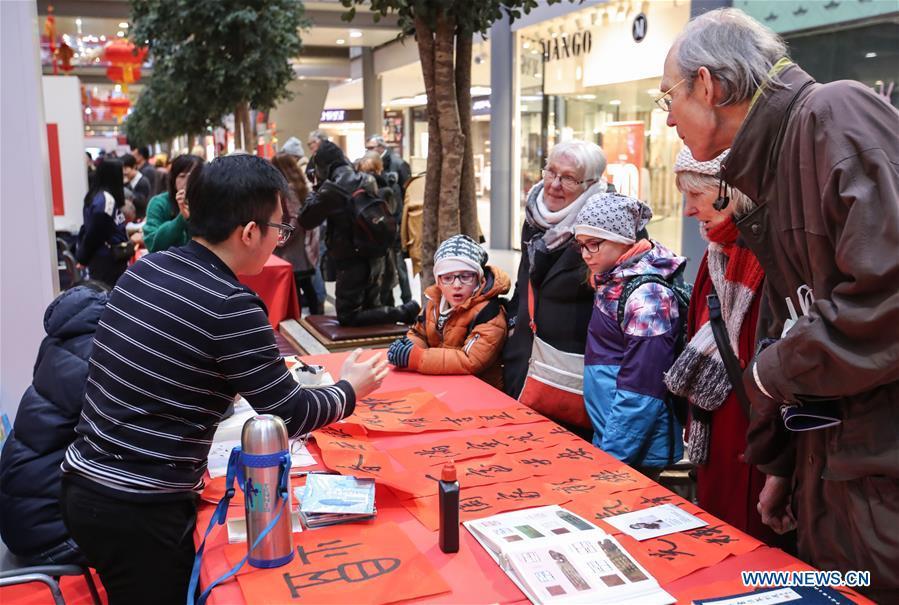 A staff member introduces Chinese Spring Festival couplets to visitors in a shopping mall at Potsdamer Platz in Berlin, capital of Germany, on Jan. 24, 2019. \
