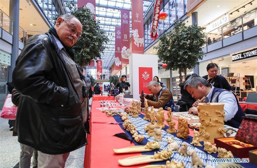 A visitor looks at traditional Chinese wood carvings in a shopping mall at Potsdamer Platz in Berlin, capital of Germany, on Jan. 24, 2019. \