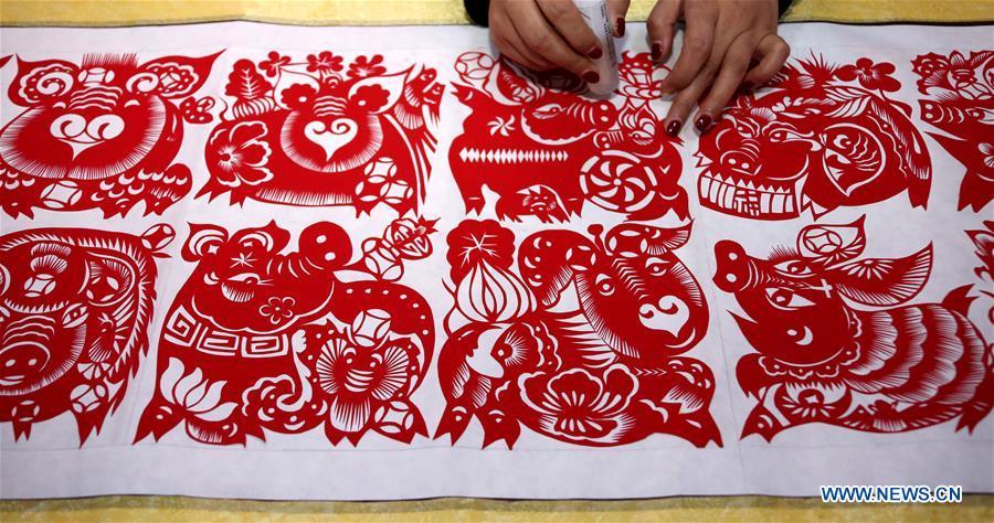 Folk artist Shi Hongxia creates a pig-themed paper cutting artwork at home in Tengzhou City, east China\'s Shandong Province, Jan. 31, 2019. Shi has spent two months to create the artwork, which is 9 meters long and features 100 pig figures, to greet the coming of the Year of the Pig. (Xinhua/Sun Zhongzhe)