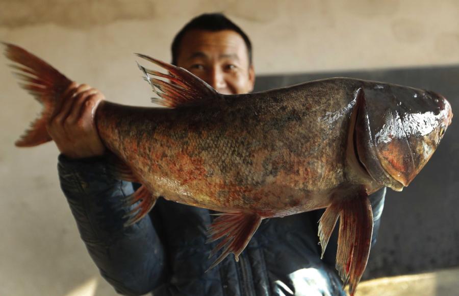A man shows off a fish he caught from Yeya Lake. (Photo by Tian Baoxi/Provided to chinadaily.com.cn)
