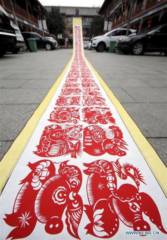 Folk artist Shi Hongxia shows a pig-themed paper cutting artwork in Tengzhou City, east China\'s Shandong Province, Jan. 31, 2019. Shi has spent two months to create the artwork, which is 9 meters long and features 100 pig figures, to greet the coming of the Year of the Pig. (Xinhua/Sun Zhongzhe)