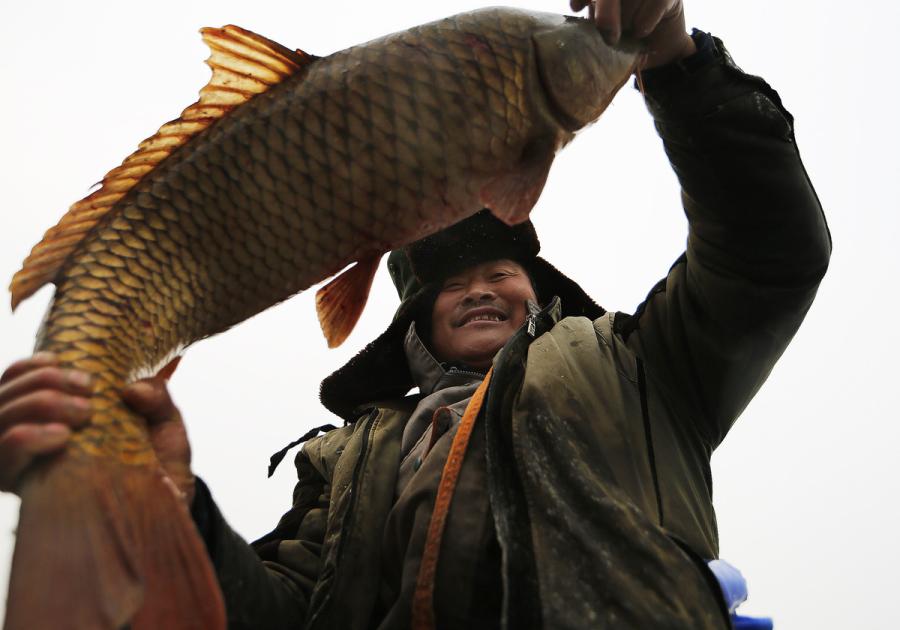 A man shows off the fish he caught from Yeya Lake. (Photo by Tian Baoxi/Provided to chinadaily.com.cn)