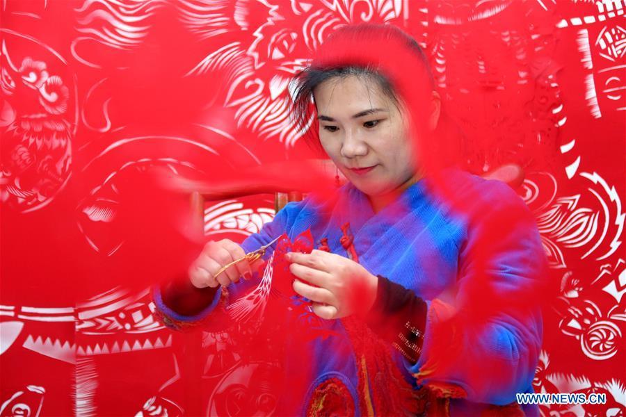 Folk artist Shi Hongxia creates a pig-themed paper cutting artwork at home in Tengzhou City, east China\'s Shandong Province, Jan. 31, 2019. Shi has spent two months to create the artwork, which is 9 meters long and features 100 pig figures, to greet the coming of the Year of the Pig. (Xinhua/Sun Zhongzhe)