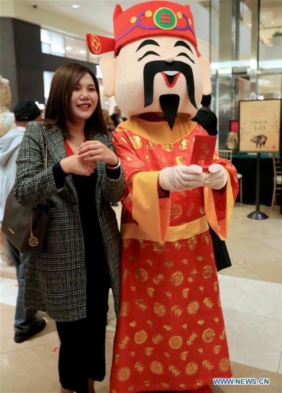 A woman poses with a staff member dressed up as the Chinese God of Wealth during a Chinese Lunar New Year celebration at South Coast Plaza in Costa Mesa, California, the United States, on Jan. 31, 2019. South Coast Plaza held a variety of activities such as dragon dance, lion dance, singing and dancing shows to celebrate the upcoming Chinese Lunar New Year. (Xinhua/Li Ying)