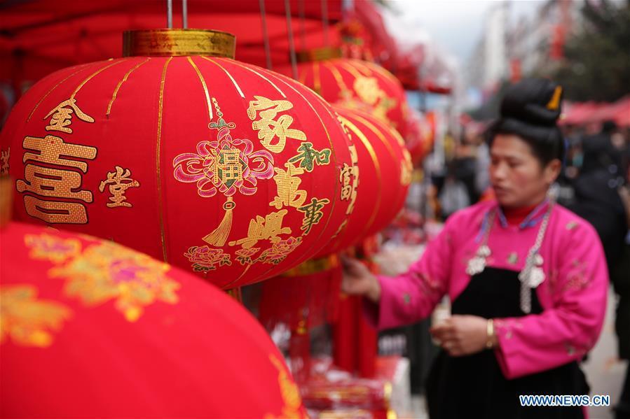 A woman selects red lanterns at a local market in Danzhai County, southwest China\'s Guizhou Province, Jan. 31, 2019. People are busy buying goods in Guizhou for the upcoming Spring Festival, which falls on Feb. 5 this year. (Xinhua/Huang Xiaohai)