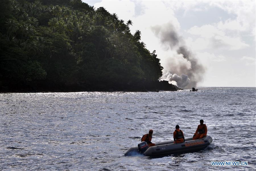 Search and Rescue (SAR) team members row a boat as they watch the lava lane of Mount Karangetang in the background in North Sulawesi, Indonesia, Feb. 10, 2019. Hot lava and volcanic materials that spewed from Mount Karangetang volcano in Indonesia\'s North Sulawesi province cut roads and buried bridges, while bad weather hampered evacuation operations, officials said on Saturday. Local authorities were trying to evacuate 508 villagers from the area. (Xinhua/Stringer)