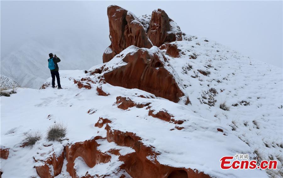 Tourists visit the snow-covered Danxia landform in Sunan Yugur Autonomous County, Northwest China\'s Gansu Province during the Spring Festival holiday. The Danxia landform is a unique type of geomorphology formed from red-colored sandstone and characterized by steep cliffs. (Photo: China News Service/Wang Jiang)
