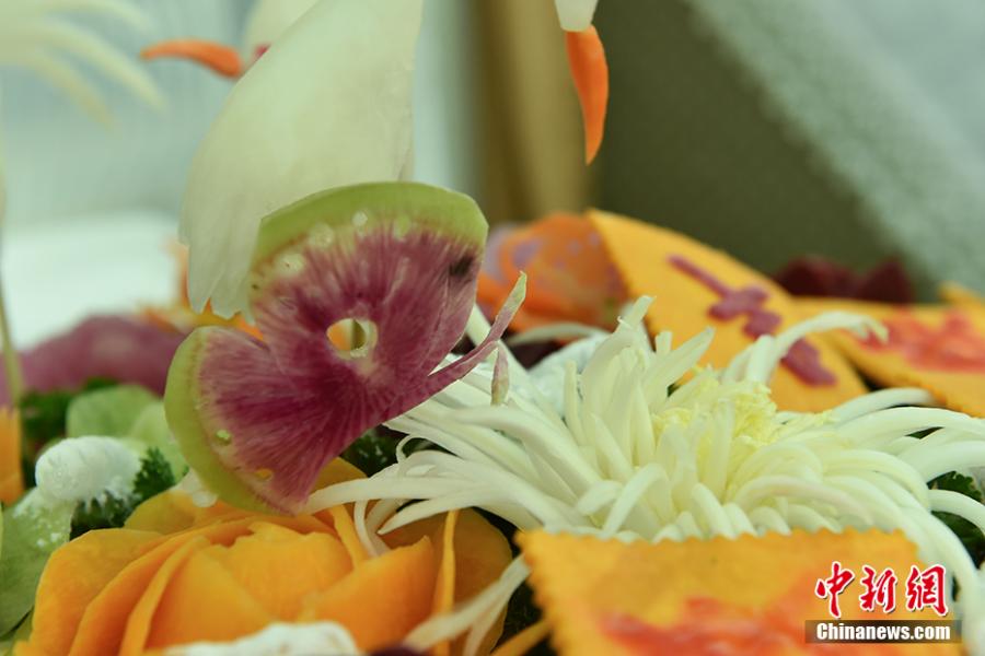 Wang Jinliang shows his food carving creations on a train in Beijing during Spring Festival, China\'s Lunar New Year. Wang, 59, has worked on trains for more than 40 years, starting as a cook in 1978 before moving to roles as chef, kitchen head and now Party chief of the passengers service department. As the 2019 Spring Festival was his last one on duty, he spent 80 yuan ($12) buying fruits and vegetables including watermelon, carrot and Chinese cabbage to show his carving creations. Wang also said his skill in making fancy food garnishes enabled him to contribute to marking important occasions in his job, such as the first train from Beijing to Shenzhen in 1996. (Photo: China News Service/Zhai Lu)