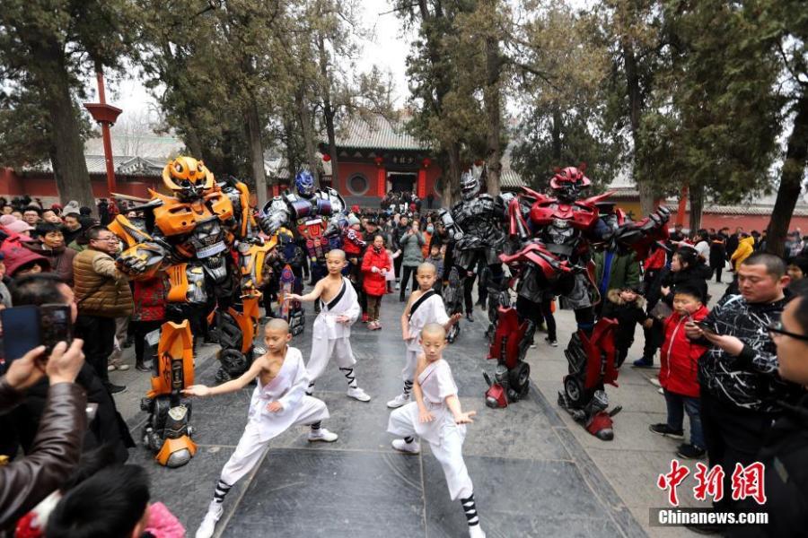 Students of kung fu at Shaolin Temple pose with Transformer-like statues in Dengfeng City, Central China\'s Henan Province, Feb. 7, 2019, as many tourists visit the famed Buddhist temple during the Lunar New Year holiday. (Photo: China News Service/Wang Zhongju)