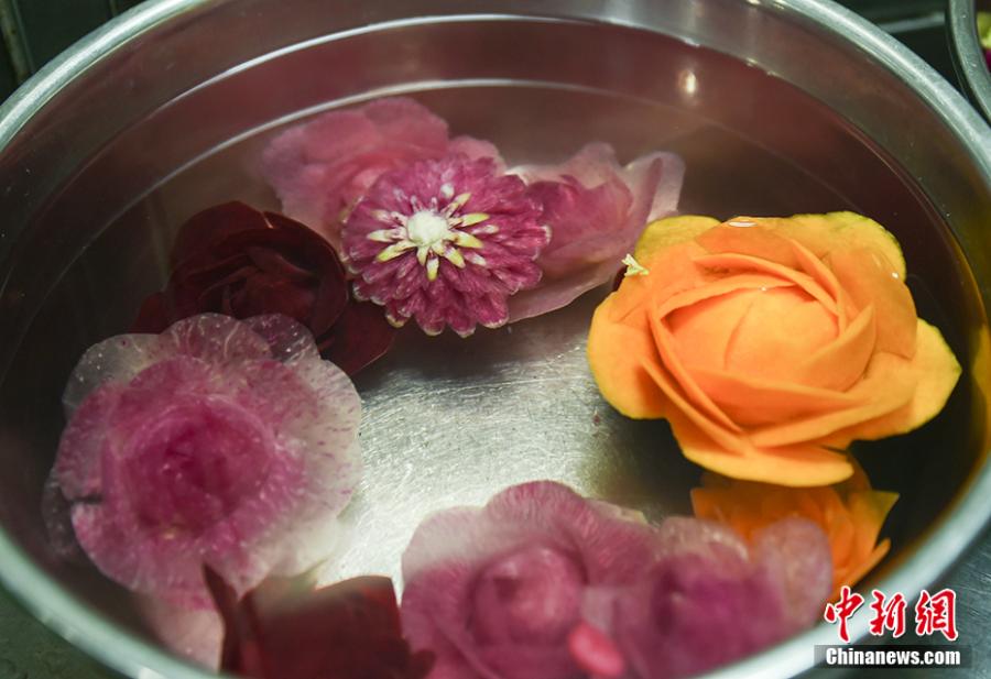 Wang Jinliang shows his food carving creations on a train in Beijing during Spring Festival, China\'s Lunar New Year. Wang, 59, has worked on trains for more than 40 years, starting as a cook in 1978 before moving to roles as chef, kitchen head and now Party chief of the passengers service department. As the 2019 Spring Festival was his last one on duty, he spent 80 yuan ($12) buying fruits and vegetables including watermelon, carrot and Chinese cabbage to show his carving creations. Wang also said his skill in making fancy food garnishes enabled him to contribute to marking important occasions in his job, such as the first train from Beijing to Shenzhen in 1996. (Photo: China News Service/Zhai Lu)