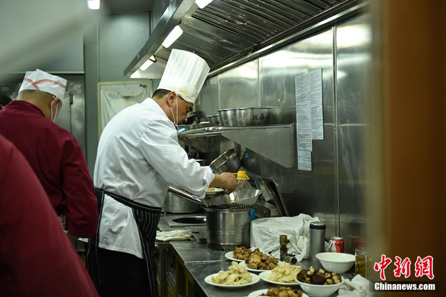 Wang Jinliang cooks in a train kitchen in Beijing during Spring Festival, China\'s Lunar New Year. Wang, 59, has worked on trains for more than 40 years, starting as a cook in 1978 before moving to roles as chef, kitchen head and now Party chief of the passengers service department. As the 2019 Spring Festival was his last one on duty, he spent 80 yuan ($12) buying fruits and vegetables including watermelon, carrot and Chinese cabbage to show his carving creations. Wang also said his skill in making fancy food garnishes enabled him to contribute to marking important occasions in his job, such as the first train from Beijing to Shenzhen in 1996. (Photo: China News Service/Zhai Lu)