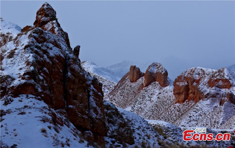 Tourists visit the snow-covered Danxia landform in Sunan Yugur Autonomous County, Northwest China\'s Gansu Province during the Spring Festival holiday. The Danxia landform is a unique type of geomorphology formed from red-colored sandstone and characterized by steep cliffs. (Photo: China News Service/Wang Jiang)