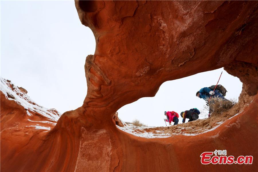 Tourists visit the snow-covered Danxia landform in Sunan Yugur Autonomous County, Northwest China\'s Gansu Province during the Spring Festival holiday. The Danxia landform is a unique type of geomorphology formed from red-colored sandstone and characterized by steep cliffs. (Photo: China News Service/Wang Jiang)