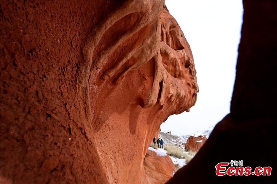 Tourists visit the snow-covered Danxia landform in Sunan Yugur Autonomous County, Northwest China\'s Gansu Province during the Spring Festival holiday. The Danxia landform is a unique type of geomorphology formed from red-colored sandstone and characterized by steep cliffs. (Photo: China News Service/Wang Jiang)