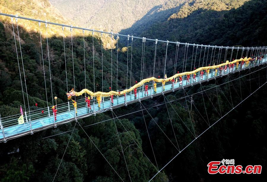 As part of Spring Festival celebrations, local people perform a dragon dance on a suspended glass bridge, some 200 meters above the ground, at a scenic area in Youxi County, East China\'s Fujian Province, Feb. 12, 2019.  (Photo: China News Service/Wang Dongming)