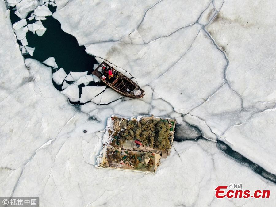 Boats are stranded in frozen sea at a port in Dalian City, Northeast China\'s Liaoning Province amid a cold front. A fisherman had to break ice to transport supplies to a marine fish culture zone. (Photo/VCG)