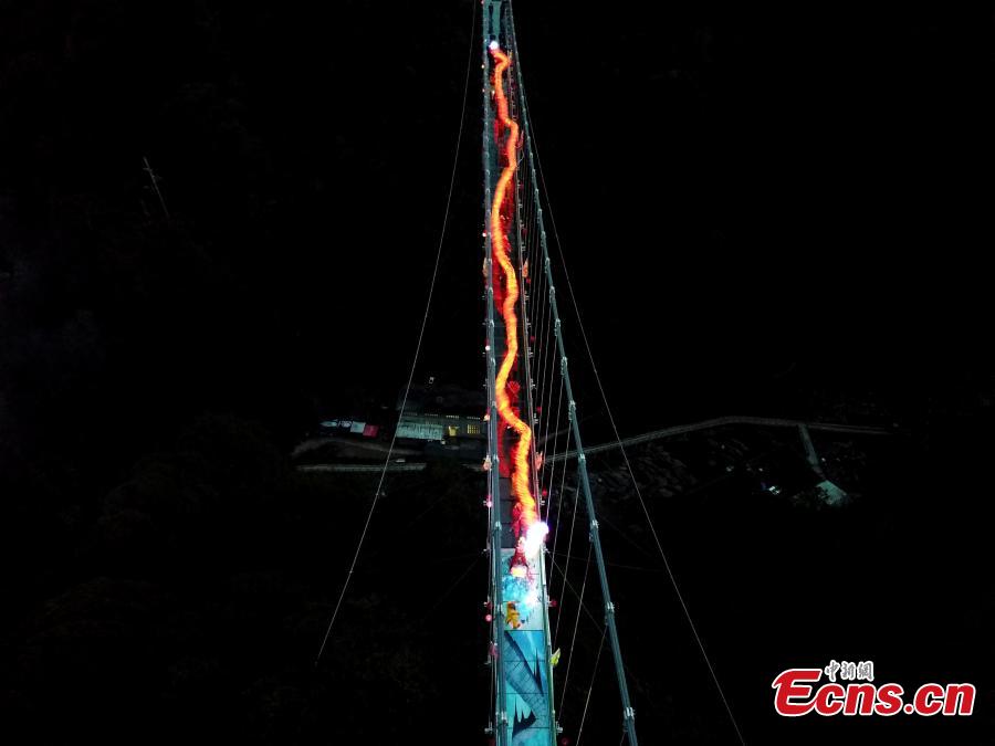 As part of Spring Festival celebrations, local people perform a dragon dance on a suspended glass bridge, some 200 meters above the ground, at a scenic area in Youxi County, East China\'s Fujian Province, Feb. 12, 2019.  (Photo: China News Service/Wang Dongming)