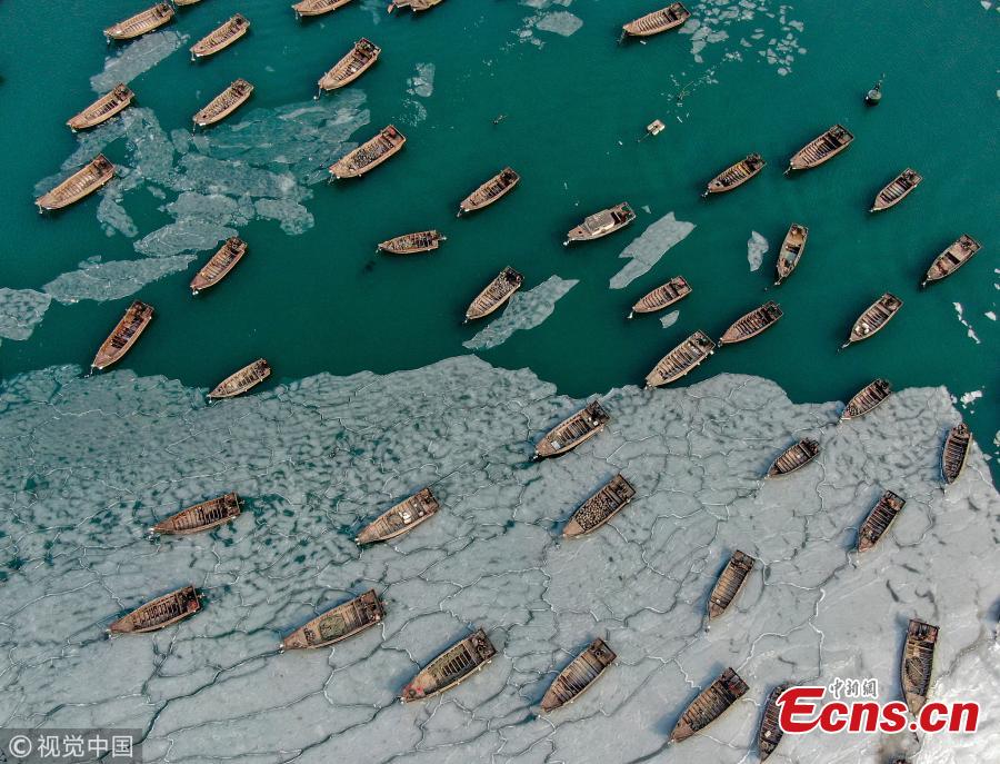 Boats are stranded in frozen sea at a port in Dalian City, Northeast China\'s Liaoning Province amid a cold front. A fisherman had to break ice to transport supplies to a marine fish culture zone. (Photo/VCG)