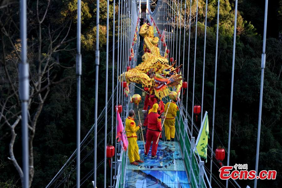 As part of Spring Festival celebrations, local people perform a dragon dance on a suspended glass bridge, some 200 meters above the ground, at a scenic area in Youxi County, East China\'s Fujian Province, Feb. 12, 2019.  (Photo: China News Service/Wang Dongming)