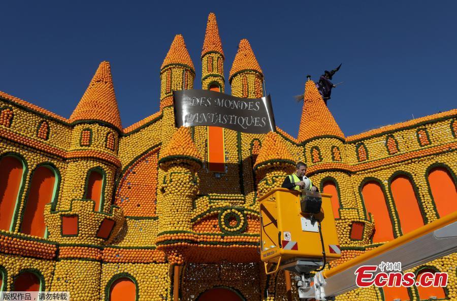 A worker puts the final touch to a sculpture made with lemons and oranges which depicts a Castle during the 86th Lemon festival around the theme \