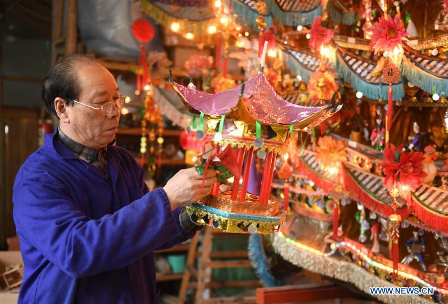 Lin Shunkui looks at his ornamental dragon at home in Beibaixiang Town of Yueqing, east China\'s Zhejiang Province, Feb. 11, 2019. Having a history of more than 400 years, the ornamental dragon, a sacrifice to pray for good fortune during the period of Lantern Festival, is popular in villages of Yueqing City in Zhejiang Province. Lin Shunkui, an inheritor of the handicraft of ornamental dragon, is born in 1956 in Dongchan Village of Beibaixiang Town. Learning the art since he was young from his father, who is a master of fine paper-cutting, Lin has been in the walk for more than 40 years and has been famous for his exquisite handicraft. The making procedures of the ornamental dragon require high standards and needs preparation of more than half a year. The craftsman must be proficient in various vocations such as paper-cutting, carpentry, painting and machinery. Usually having a height of four meters, a length of three meters and a width of two meters, the ornamental dragon displays about 300 figures in more than 80 cabinets, which are driven by gears hidden inside the dragon body. The handicraft of ornamental dragon was listed as one of the national intangible cultural heritages in October of 2014. (Xinhua/Weng Xinyang)