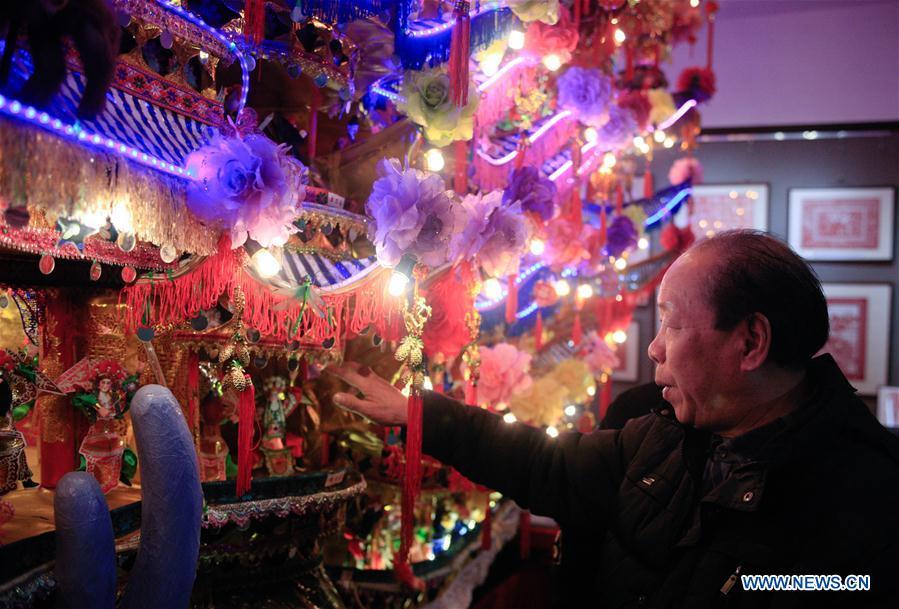 Lin Shunkui looks at his ornamental dragon at home in Beibaixiang Town of Yueqing, east China\'s Zhejiang Province, Feb. 11, 2019. Having a history of more than 400 years, the ornamental dragon, a sacrifice to pray for good fortune during the period of Lantern Festival, is popular in villages of Yueqing City in Zhejiang Province. Lin Shunkui, an inheritor of the handicraft of ornamental dragon, is born in 1956 in Dongchan Village of Beibaixiang Town. Learning the art since he was young from his father, who is a master of fine paper-cutting, Lin has been in the walk for more than 40 years and has been famous for his exquisite handicraft. The making procedures of the ornamental dragon require high standards and needs preparation of more than half a year. The craftsman must be proficient in various vocations such as paper-cutting, carpentry, painting and machinery. Usually having a height of four meters, a length of three meters and a width of two meters, the ornamental dragon displays about 300 figures in more than 80 cabinets, which are driven by gears hidden inside the dragon body. The handicraft of ornamental dragon was listed as one of the national intangible cultural heritages in October of 2014. (Xinhua/Zhu Weixi)