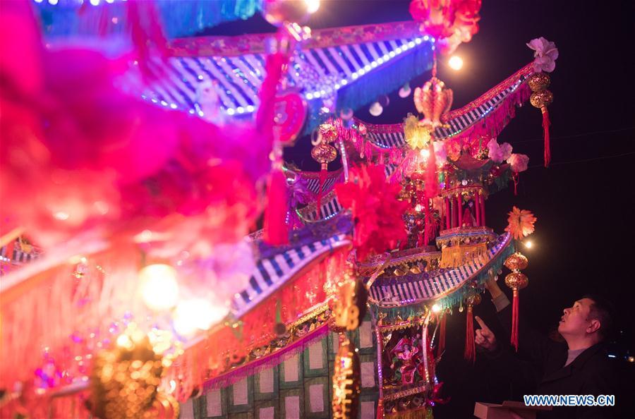 A villager checks ornamental dragon during parade in Xiliuzhai Village of Beibaixiang Town of Yueqing, east China\'s Zhejiang Province, Feb. 12, 2019. Having a history of more than 400 years, the ornamental dragon, a sacrifice to pray for good fortune during the period of Lantern Festival, is popular in villages of Yueqing City in Zhejiang Province. Lin Shunkui, an inheritor of the handicraft of ornamental dragon, is born in 1956 in Dongchan Village of Beibaixiang Town. Learning the art since he was young from his father, who is a master of fine paper-cutting, Lin has been in the walk for more than 40 years and has been famous for his exquisite handicraft. The making procedures of the ornamental dragon require high standards and needs preparation of more than half a year. The craftsman must be proficient in various vocations such as paper-cutting, carpentry, painting and machinery. Usually having a height of four meters, a length of three meters and a width of two meters, the ornamental dragon displays about 300 figures in more than 80 cabinets, which are driven by gears hidden inside the dragon body. The handicraft of ornamental dragon was listed as one of the national intangible cultural heritages in October of 2014. (Xinhua/Weng Xinyang)