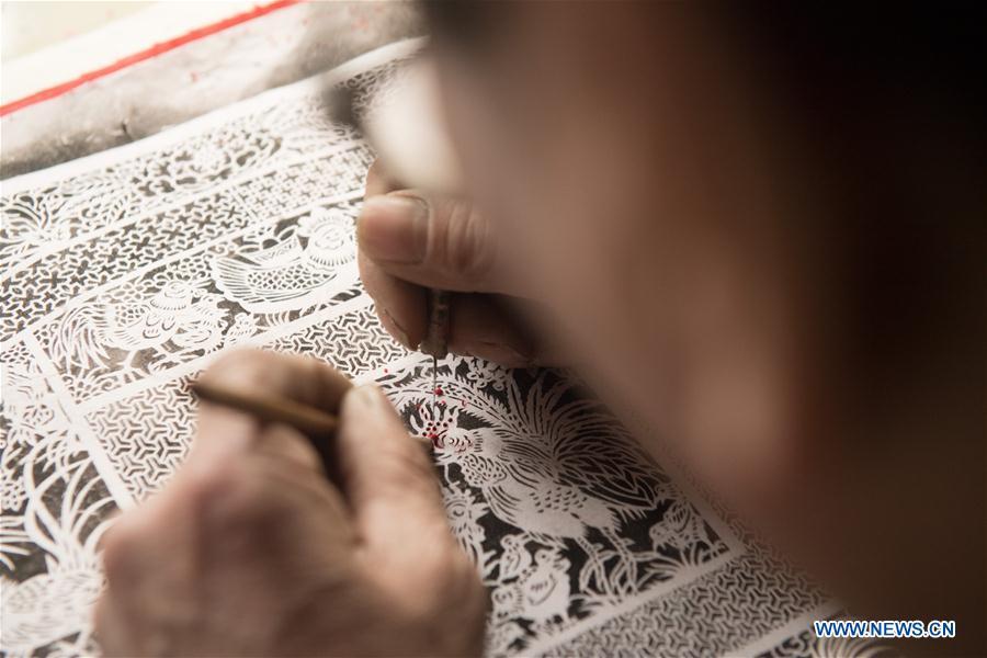 Lin Shunkui shows paper-cutting skills at home in Beibaixiang Town of Yueqing, east China\'s Zhejiang Province, Feb. 12, 2019. Having a history of more than 400 years, the ornamental dragon, a sacrifice to pray for good fortune during the period of Lantern Festival, is popular in villages of Yueqing City in Zhejiang Province. Lin Shunkui, an inheritor of the handicraft of ornamental dragon, is born in 1956 in Dongchan Village of Beibaixiang Town. Learning the art since he was young from his father, who is a master of fine paper-cutting, Lin has been in the walk for more than 40 years and has been famous for his exquisite handicraft. The making procedures of the ornamental dragon require high standards and needs preparation of more than half a year. The craftsman must be proficient in various vocations such as paper-cutting, carpentry, painting and machinery. Usually having a height of four meters, a length of three meters and a width of two meters, the ornamental dragon displays about 300 figures in more than 80 cabinets, which are driven by gears hidden inside the dragon body. The handicraft of ornamental dragon was listed as one of the national intangible cultural heritages in October of 2014. (Xinhua/Weng Xinyang)