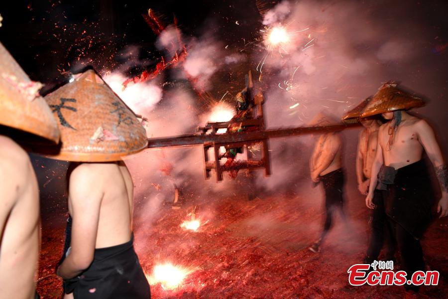 Shirtless men carrying the statue of a local deity perform amid firecrackers and sparklers during a folk festival in Yanfeng Village in Quanzhou City, East China\'s Fujian Province, Feb. 18, 2019. The tradition formed in the Ming Dynasty (1368-1644) is part of Lantern Festival celebrations on the 15th day of the first lunar month, or Feb. 19 this year. (Photo: China News Service/Wang Dongming)