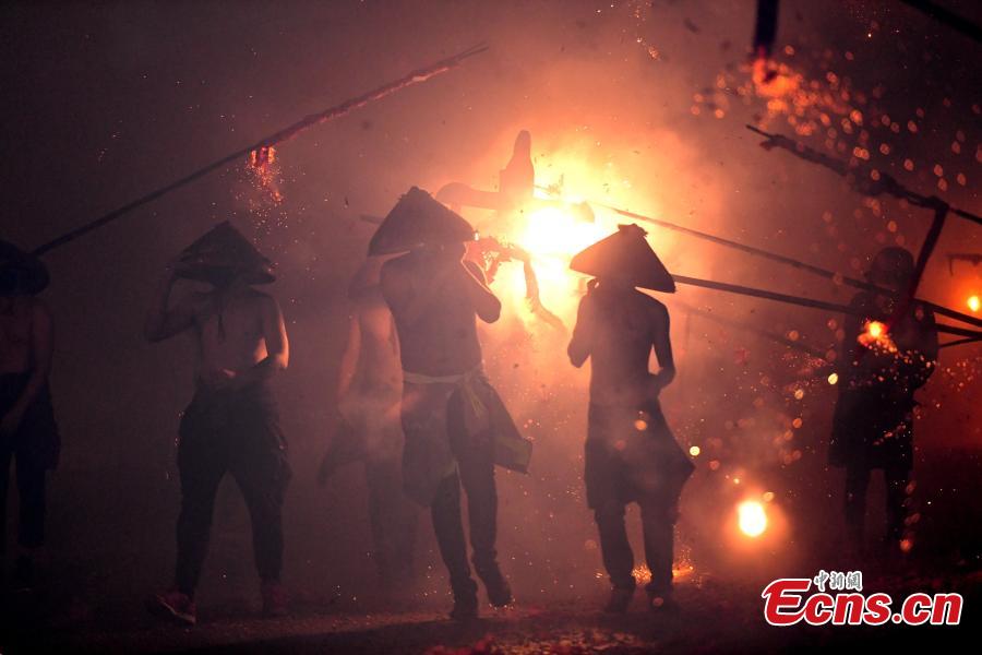 Shirtless men carrying the statue of a local deity perform amid firecrackers and sparklers during a folk festival in Yanfeng Village in Quanzhou City, East China\'s Fujian Province, Feb. 18, 2019. The tradition formed in the Ming Dynasty (1368-1644) is part of Lantern Festival celebrations on the 15th day of the first lunar month, or Feb. 19 this year. (Photo: China News Service/Wang Dongming)