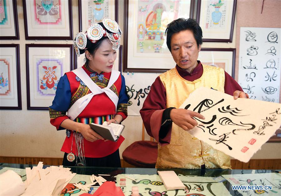 Fan Yongzhen (L), deputy to China\'s 13th National People\'s Congress (NPC), carries out a research on the Dongba pictographic language at Yushuizhai Village of Yulong Naxi Autonomous County in Lijiang, southwest China\'s Yunnan Province, Feb. 13, 2019. Working as vice curator of the Cultural Center in Lijiang city, Fan has devoted herself to the career of protecting and promoting local ethnic cultures. Besides, she also contributes to the mass culture construction work by sending performances to rural areas together with her colleagues. As a deputy to NPC, China\'s top legislature, Fan will put more efforts into the building of cultural industries integrated with digital technologies in underdeveloped areas so as to improve local cultural development. (Xinhua/Yang Zongyou)