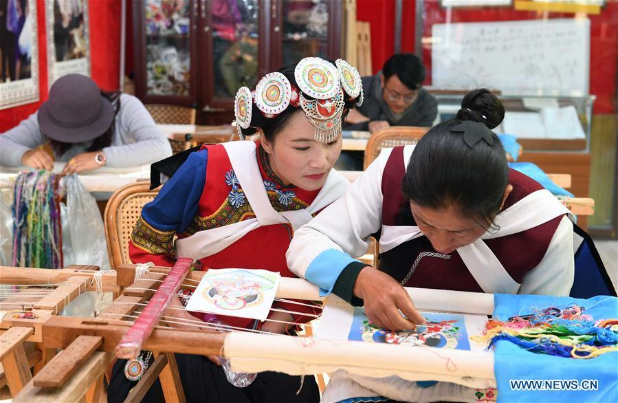Fan Yongzhen(L, front), deputy to China\'s 13th National People\'s Congress (NPC), carries out a research on dianxiu embroidery at Baisha Old Town of Yulong Nax Autonomous County in Lijiang, southwest China\'s Yunnan Province, Feb. 13, 2019. Working as vice curator of the Cultural Center in Lijiang city, Fan has devoted herself to the career of protecting and promoting local ethnic cultures. Besides, she also contributes to the mass culture construction work by sending performances to rural areas together with her colleagues. As a deputy to NPC, China\'s top legislature, Fan will put more efforts into the building of cultural industries integrated with digital technologies in underdeveloped areas so as to improve local cultural development. (Xinhua/Yang Zongyou)