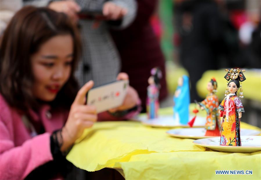 A visitor takes a photo of the dough modelling on the annual dough modelling exhibition held in Nanzhang Village of Xiulin Town in Jingxing County, Shijiazhuang, capital of north China\'s Hebei Province, on Feb. 22, 2019. The exquisitely crafted and colorful dough modelling on display attracted a great number of visitors to appreciate the beauty. The Nanzhang dough modelling was listed as one of the provincial level intangible cultural heritages in 2011. (Xinhua/Wang Baolong)
