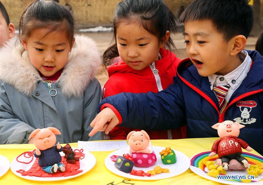 Three children watch the dough modelling on the annual dough modelling exhibition held in Nanzhang Village of Xiulin Town in Jingxing County, Shijiazhuang, capital of north China\'s Hebei Province, on Feb. 22, 2019. The exquisitely crafted and colorful dough modelling on display attracted a great number of visitors to appreciate the beauty. The Nanzhang dough modelling was listed as one of the provincial level intangible cultural heritages in 2011. (Xinhua/Zhang Xiuke)