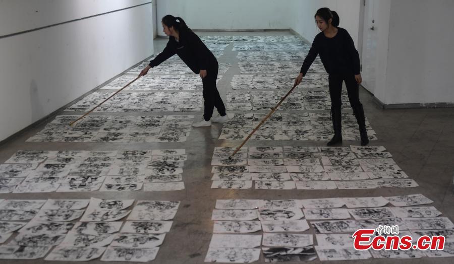 Judges use bamboo sticks to help them review paintings by applicants to the Shandong University of Arts in Jinan City, Shandong Province, Feb. 28, 2019. More than 10,000 paintings were placed in a corridor for judges to grade. (Photo: China News Service/Zhang Yong)