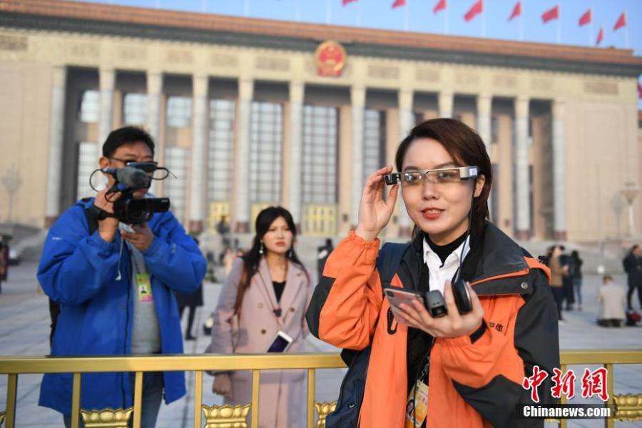 A reporter wears virtual reality (VR) glasses while covering the second session of the 13th National People\'s Congress at the Great Hall of the People in Beijing on Tuesday, March 5, 2019. The VR glasses can record the voice of the wearer, and the tiny camera installed on the frame of the glasses can capture high-definition videos. (Photo/China News Service)