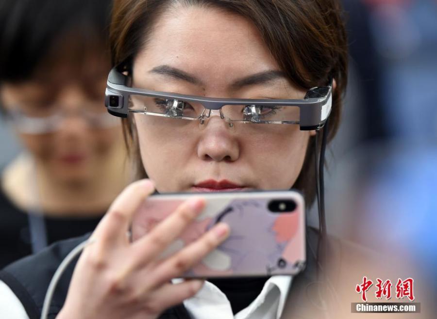 A reporter wears virtual reality (VR) glasses while covering the second session of the 13th National People\'s Congress at the Great Hall of the People in Beijing on Tuesday, March 5, 2019. The VR glasses can record the voice of the wearer, and the tiny camera installed on the frame of the glasses can capture high-definition videos. (Photo/China News Service)