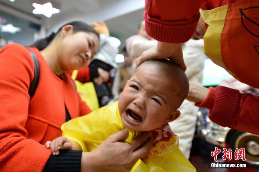 A child gets a haircut at a barbershop in Baokang County, Central China\'s Hubei Province, March 8, 2019. March 8 marks traditional Chinese festival Long Tai Tou (dragon head raising), which refers to the start of spring and farming. During the festival, held on the second day of the second month of the lunar calendar, people play dragon lanterns, eat noodles, shave their hair, and pray for luck.(Photo: China News Service/Yang Tao)
