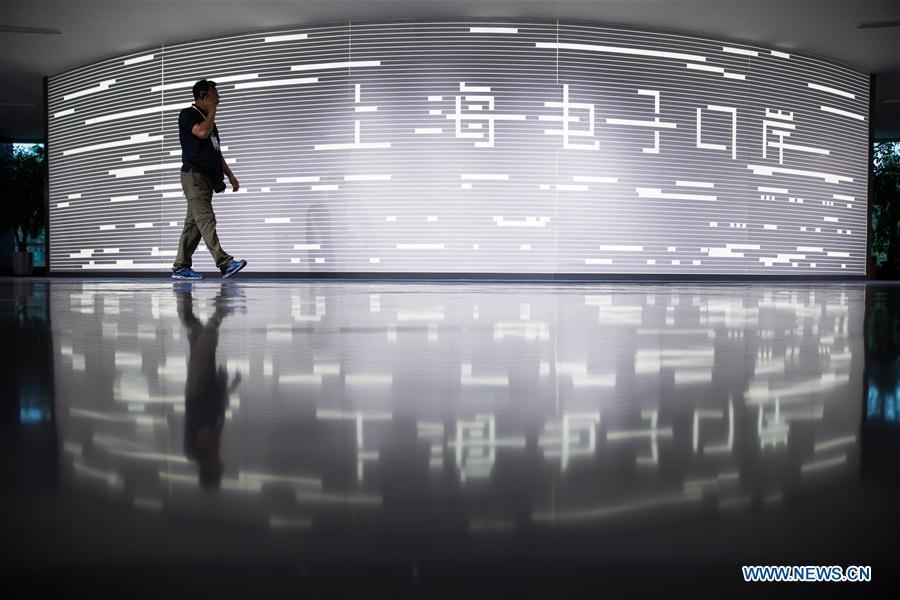 A man passes by a signboard for Shanghai E-port in Shanghai, east China, Aug. 12, 2018. (Xinhua/Jin Liwang)