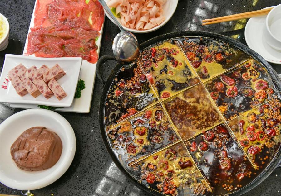 More than 5,000 jars of soybean sauce, essential for hotpot, are displayed in Wenchang village in suburban Chongqing. (XIE QIKUN/FOR CHINA DAILY)
Thriving business

According to the Chongqing Hotpot Association, there are more than 50,000 such restaurants in the city, employing at least 3.5 million people. The entire industry is estimated to be worth hundreds of billions of yuan.

The traditional spicy chili oil hotpot is divided into nine sections because in the past, several people shared one pot and put food in their own sections.

To meet the demands of those who cannot eat such spicy food, Chongqing hotpot restaurant owners have developed three soup bases: spicy chili oil broth, a clear broth (usually chicken soup) and a broth that is a mix of the two.

Local people say the development of Chongqing hotpot is linked closely with women from the city who own most of the well-known restaurants. The best-known is He Yongzhi, owner of the Little Swan chain.

The 65-year-old is director of the Chongqing Hotpot Association, and is often known as \