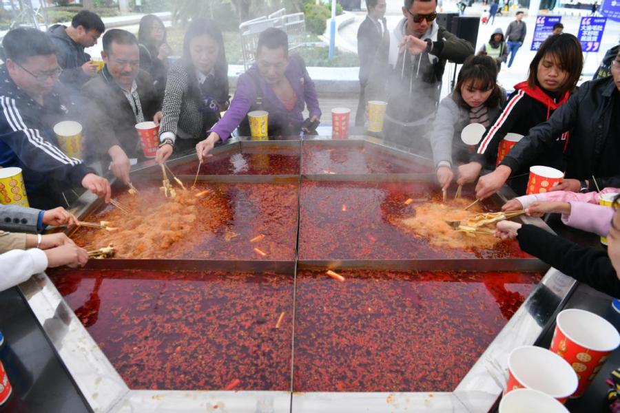 A hotpot festival is staged in Kunming, Yunnan Province. (Photo/CHINA NEWS SERVICE)
Good meat was brought in and sold to the upper and middle classes. The internal organs, including the stomach and kidneys, were discarded or sold cheaply. Porters picked up or bought the organs and cooked them in a boiling pot with a spicy sauce and ate the food by the rivers.

According to Feng Tu Shi Zhi, a folklore magazine published in the 1940s, the first hotpot restaurant in the city was Ma Zheng Xing, owned by the Ma brothers.

Legend has it that the two brothers tasted the street food and were hooked. They saw a business opportunity and introduced hotpot in their restaurants in the 1930s.

In 1937, the Kuomintang government led by Chiang Kai-shek established Chongqing as the country\'s capital. The southwestern city went on to play a critical role in the Asian theater of World War II.

At the time, the city witnessed a sudden influx of government officials, bankers, businessmen, scholars, diplomats, writers and other professionals from other parts of the country.

Hotpot soon gained popularity among people from all around the world, with many of the newcomers to Chongqing loving the cuisine. Although they left the city after the war, they took their love of hotpot with them, and the cuisine\'s popularity spread.