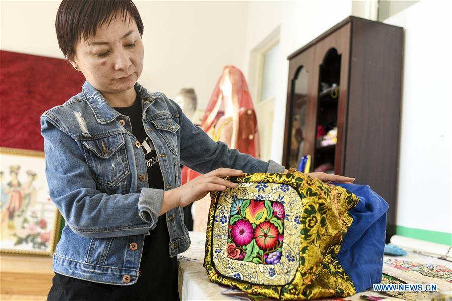 Renagul arranges her embroidery products at her workshop in Yizhou District of Hami City, northwest China\'s Xinjiang Uygur Autonomous Region, on March 8, 2019. The haute couture, literally named \