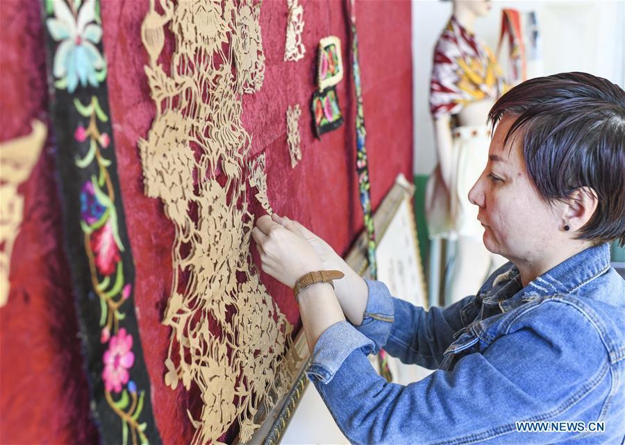 Renagul arranges papercuttings for sequins incorporated in the embroidery at her workshop in Yizhou District of Hami City, northwest China\'s Xinjiang Uygur Autonomous Region, on March 8, 2019. The haute couture, literally named \
