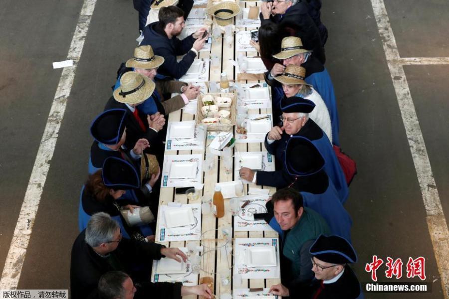 Participants attend a lunch served on a 401.22-meter-long table in the fruit and vegetable pavilion at the Rungis International Food Market during an event near Paris, France on March 17 celebrating the market’s 50th anniversary, which also aims to set a Guinness World Record.(Photo/Agencies)