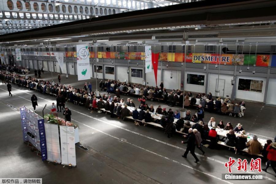 Participants attend a lunch served on a 401.22-meter-long table in the fruit and vegetable pavilion at the Rungis International Food Market during an event near Paris, France on March 17 celebrating the market’s 50th anniversary, which also aims to set a Guinness World Record.(Photo/Agencies)