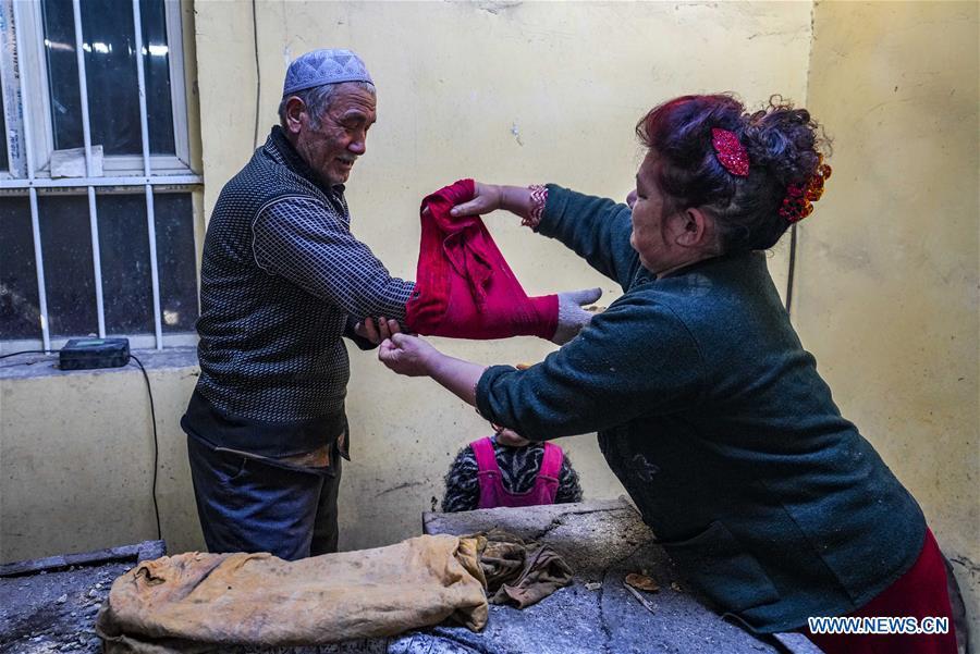A woman helps her husband wrap a towel around his arm as a preparation before baking \