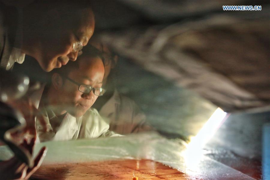 Wang Zongxun (L), curator of a museum of Jinping Writs, guides as a staff worker restores a document at the museum in Jinping County, southwest China\'s Guizhou Province, March 18, 2019. Dating back to the Ming Dynasty (1368-1644), \