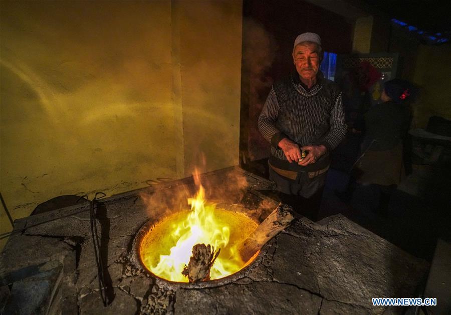 A baker checks the wood fire in an oven used to bake \