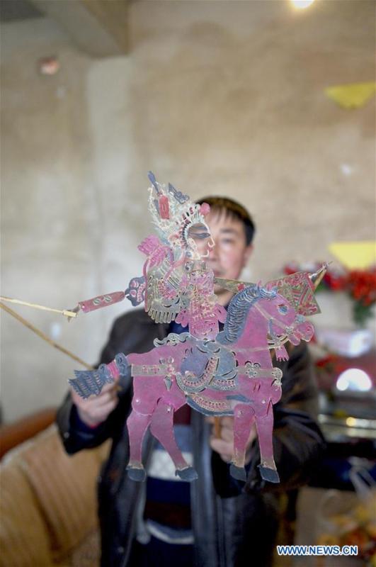 Pan Mingsheng displays shadow puppet made by himself at Xinzhai Township of Weiyuan County in Dingxi City, northwest China\'s Gansu province, March 13, 2019. Many local folk artists concentrate on inheriting and passing down the folk art of shadow puppet performing and making in Gansu. They devote themselves to the study of the art and also organize various events to popularize the art. (Xinhua/Li Xiao)